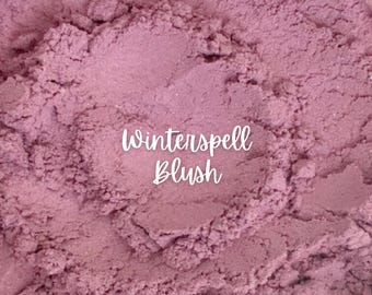 May include: Close-up of a pink blush powder with the text "Winterspell Blush" written on top.