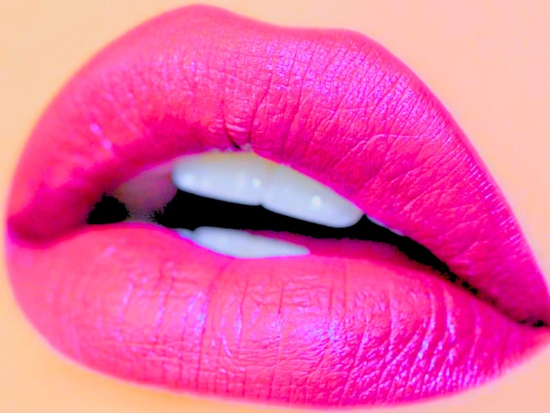 Pu&ograve; includere: Primo piano di un paio di labbra dipinte con rossetto rosa brillante. Le labbra sono leggermente socchiuse, rivelando denti bianchi contro uno spazio nero. Lo sfondo &egrave; di un colore pesca tenue.