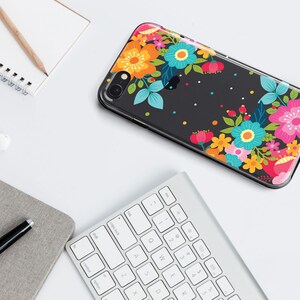 May include: A clear phone case with a black background and a colorful floral design. The flowers are pink, blue, yellow, orange, and green. The case has a white border.