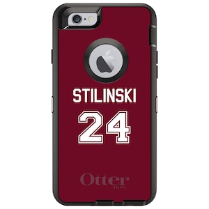 May include: A maroon OtterBox phone case with a white design. The design features the name "Stilinski" and the number "24" in a white, bold font.