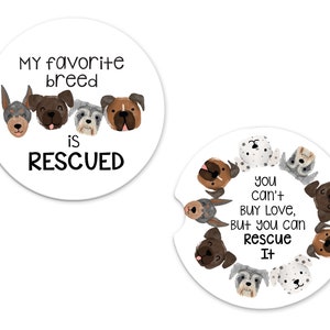 May include: Two round white coasters with black text and illustrations of dogs. The first coaster says "My favorite breed is RESCUED" and features four dog faces. The second coaster says "You can't buy love, but you can rescue it" and features eight dog faces.
