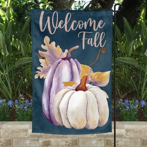 May include: Welcome Fall garden flag with a blue background and two pumpkins. The pumpkins are painted white and purple with a yellow leaf behind them.