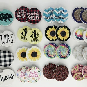 May include: Set of 12 round ceramic coasters with various designs. The designs include a black and white checkered pattern, a sunflower, a peace sign, a mandala, a bee, a tie-dye pattern, a marble pattern, a leopard print, a paisley pattern, and text that reads "Mama", "Min'yours", "Adventure Awaits", "Chaos Coordinator", "Happy", "Good Vibes Only", "Hi Hers", "Bud Cutte", and "Buckle Up Buttercup".