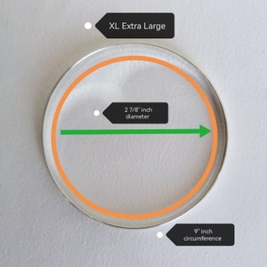 May include: A close-up of a clear glass circle with an orange ring around the edge. The circle is labeled "XL Extra Large" and has a diameter of 2 7/8 inches and a circumference of 9 inches.