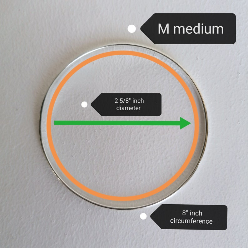 May include: A silver bangle bracelet with an orange inner circle. The bracelet is labeled "M medium" and has a diameter of 2 5/8 inches and a circumference of 8 inches.