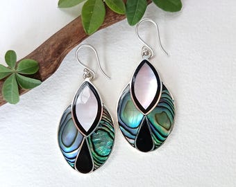 May include: A pair of silver-toned drop earrings with an abalone shell design. Each earring features a pearlescent white top section, a black bottom section, and iridescent blue-green abalone shell in the middle. The earrings hang from silver hooks.