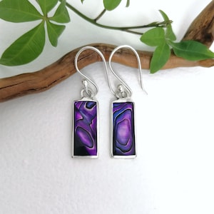 Può includere: Un paio di orecchini pendenti in argento con intarsi rettangolari in madreperla di abalone viola.