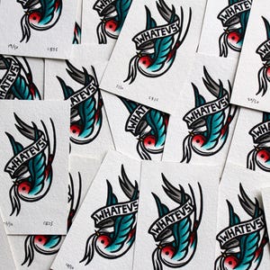 K&ouml;nnte beinhalten: Eine Sammlung kleiner, wei&szlig;er quadratischer Karten mit einer blauen und gr&uuml;nen Vogel-Illustration und dem Text "WHATEVS" in einem Banner. Die Karten sind in einem zuf&auml;lligen Muster angeordnet.