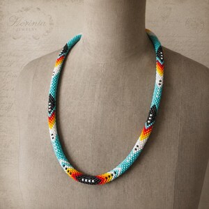 Colar de miçangas turquesa em estilo nativo americano com padrão de penas e detalhes em cores vibrantes.