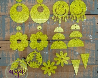May include: Assortment of yellow glitter earrings in various shapes, including circles, flowers, smiley faces, and triangles.