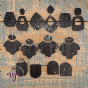 May include: A set of 14 black and white striped wood earrings with a speckled white paint finish. The earrings are in various shapes, including circles, ovals, and geometric shapes.