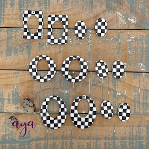 May include: A set of nine black and white checkered oval and rectangular earrings with a hole in the center. The earrings are made of wood and have a checkered pattern.