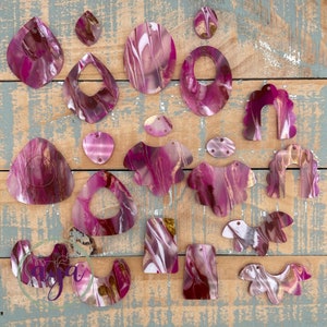 May include: Assortment of pink and gold marbled resin shapes, perfect for crafting earrings, necklaces, or other jewelry. The shapes include circles, ovals, teardrops, and more.