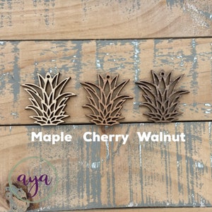 May include: Three wooden pineapple cutouts in different wood stains: maple, cherry, and walnut.