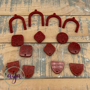 May include: A collection of red glitter resin shapes, including arches, squares, diamonds, circles, and half-circles. These shapes are perfect for crafting and jewelry making.