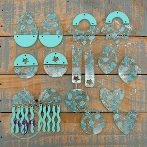 May include: Assortment of turquoise and clear resin earrings with a sea turtle and ocean wave design. The earrings are made of acrylic and are perfect for adding a touch of whimsy to any outfit.