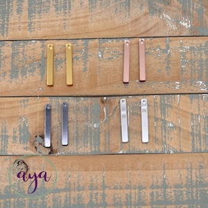 May include: Six metal bar earrings in different finishes: gold, rose gold, silver, and gunmetal. The earrings are arranged in two rows of three.