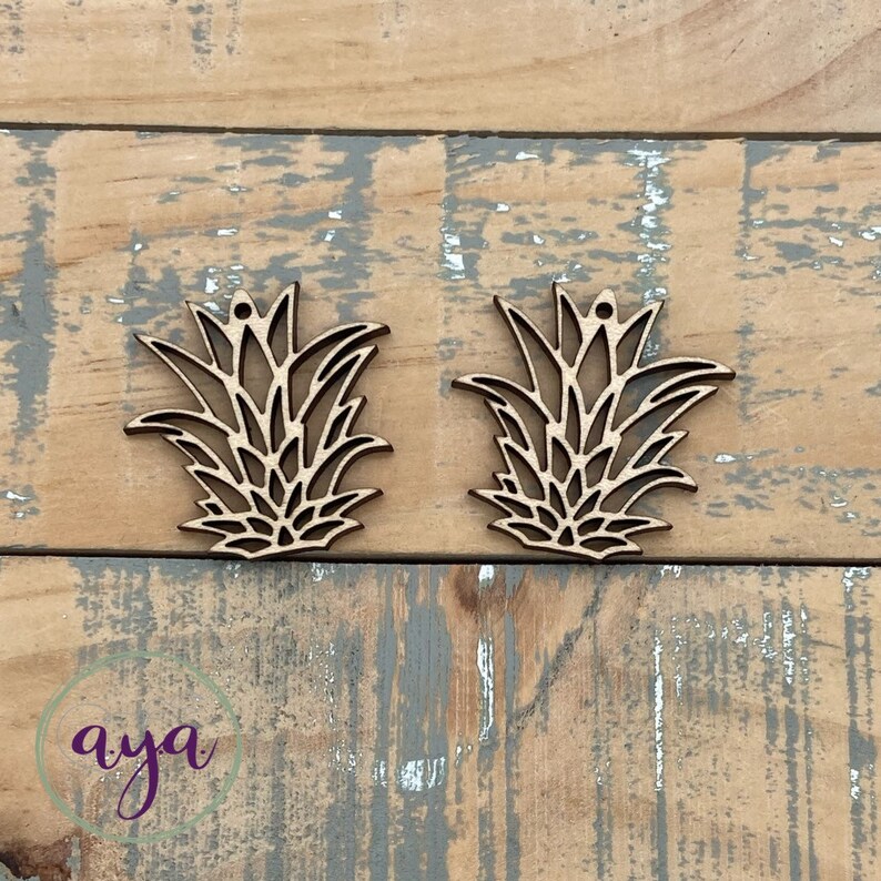 May include: Two unfinished wooden pineapple shapes with a hole at the top for hanging. The pineapples are cut out in a detailed design.