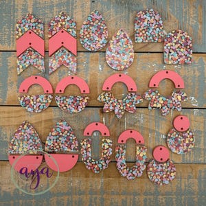 May include: Assortment of colorful resin earrings in various shapes, including teardrop, half-circle, and geometric designs. The earrings feature a speckled pattern with pink, yellow, blue, and green accents.