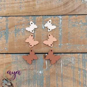 May include: Six wooden butterfly shapes in three different shades of brown. The butterflies are arranged in two rows of three, with the lightest shade on top, the medium shade in the middle, and the darkest shade on the bottom.