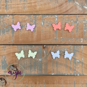 May include: Six colorful butterfly shapes made of wood. The butterflies are in two rows of three. The butterflies are in shades of pink, light blue, light green, and orange.