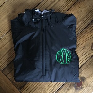 May include: Black windbreaker jacket with a green monogrammed initial "C" on the front.