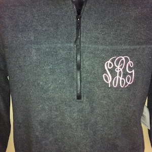 May include: A charcoal gray fleece pullover with a quarter-zip closure and a pink embroidered monogram "S.R.G."