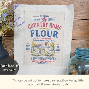 May include: A rectangular beige fabric panel featuring a printed graphic of a Country Home Flour sack. The design includes red and blue text, a red star, and two chickens in front of a farmhouse. The label measures 9 inches by 6.67 inches.