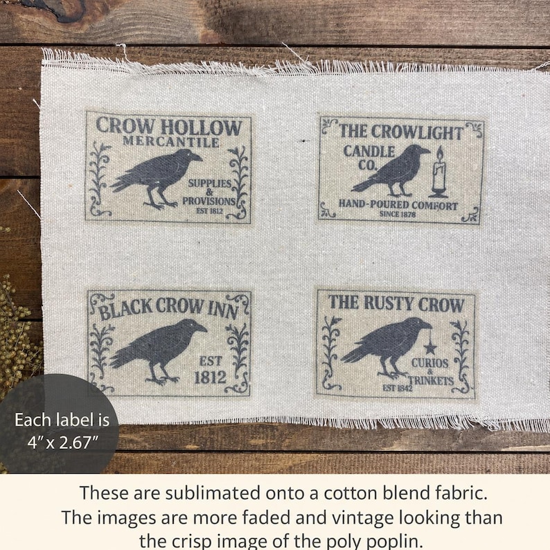May include: A rectangular piece of light beige cotton blend fabric featuring four printed labels, each measuring 4 inches by 2.67 inches. The labels display black illustrations of crows with text including Crow Hollow Mercantile, The Crowlight Candle Co., Black Crow Inn, and The Rusty Crow, all framed by decorative scrollwork.