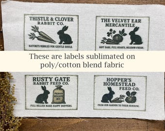 May include: Four rectangular labels with rabbit illustrations and text, including "Thistle & Clover Rabbit Co." and "The Velvet Ear Mercantile." The text "These are labels sublimated on poly/cotton blend fabric" is also present.