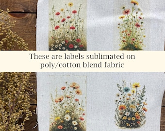 May include: Four rectangular labels with floral designs are displayed on a light-colored fabric. The labels feature various wildflowers in shades of red, yellow, orange, and white. Text on the image reads: "These are labels sublimated on poly/cotton blend fabric."