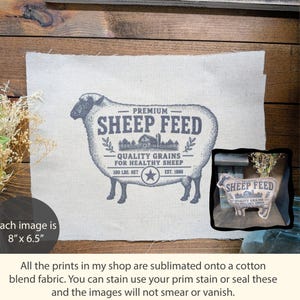 May include: A rectangular piece of off-white cotton blend fabric featuring a dark gray graphic of a sheep. The print includes the text PREMIUM SHEEP FEED, QUALITY GRAINS FOR HEALTHY SHEEP, 100 LBS. NET, and EST. 1886. The fabric measures 8 inches by 6.5 inches.