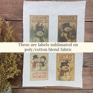 May include: Four rectangular labels with winter-themed snowman illustrations and text. The labels are printed on a light-colored fabric. The text includes "JOY TO THE WORLD", "WINTER BLESSINGS", and "LET IT SNOW". The text "These are labels sublimated on poly/cotton blend fabric" is also present.