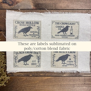 May include: Four rectangular labels with crow illustrations and text on a light beige fabric. The labels read "Crow Hollow Mercantile," "The Crowlights Candle Co.," "Black Crow Inn," and "The Rusty Crow Curios & Trinkets." The text "These are labels sublimated on poly/cotton blend fabric" is also present.