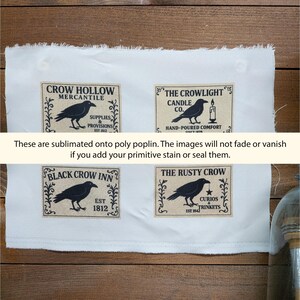 May include: A white poly poplin fabric sheet featuring four rectangular labels with black crow illustrations and text: Crow Hollow Mercantile, The Crowlight Candle Co., Black Crow Inn, and The Rusty Crow, with frayed edges on the top and bottom.