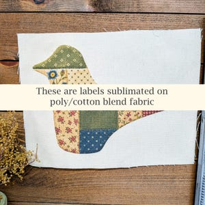 May include: A rectangular piece of off-white poly/cotton blend fabric featuring a bird-shaped graphic composed of various patchwork-style patterns in green, blue, red, and yellow. The text "These are labels sublimated on poly/cotton blend fabric" is printed across the center of the bird image.