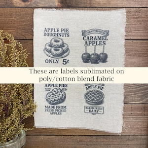 May include: A piece of fabric with four vintage-style food labels printed in gray. The labels feature illustrations of apple pie, doughnuts, and caramel apples. Text includes "Apple Pie Doughnuts," "Caramel Apples," and "Apple Pies."
