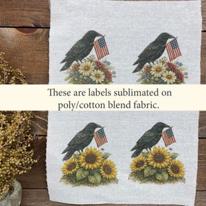 May include: Four fabric labels featuring a black crow holding a small American flag. The crow is perched atop a floral arrangement of daisies and sunflowers. The text on the image reads: "These are labels sublimated on poly/cotton blend fabric."