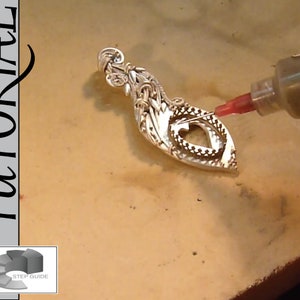 May include: A tutorial on simple soldering for artisan jewellery. The image shows a silver pendant being soldered with a syringe-like tool. The pendant has an open heart design. The text "Simple Soldering - Artisan Grade TUTORIAL" is visible.