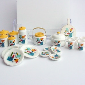 May include: A miniature tea set with a yellow, blue, and red geometric pattern. The set includes a teapot, creamer, sugar bowl, four cups, four saucers, and a serving dish.