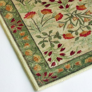 Puede incluir: Una alfombra beige con un patr&oacute;n floral verde y rojo. La alfombra tiene un borde de color crema con flecos.
