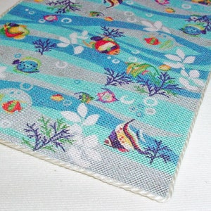 May include: A blue and white fabric with a repeating pattern of colourful fish, seaweed, and bubbles. The fabric has a white border.