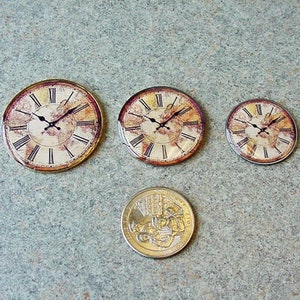 May include: Three round, decorative, vintage-style clocks with Roman numeral faces and a distressed, aged look. The clocks are different sizes, with the largest clock being about the size of a standard US quarter.