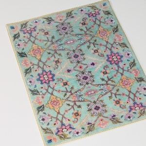 May include: A turquoise rug with a floral pattern in shades of pink, yellow, and purple. The rug has a gold border.
