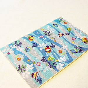 May include: A blue and grey rug with a pattern of colourful fish, bubbles, and seaweed. The rug has a white border.