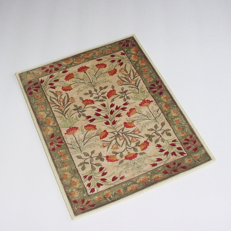 Puede incluir: Una alfombra beige con un patr&oacute;n floral con flores rojas, naranjas y verdes. La alfombra tiene un borde verde con un ribete blanco.