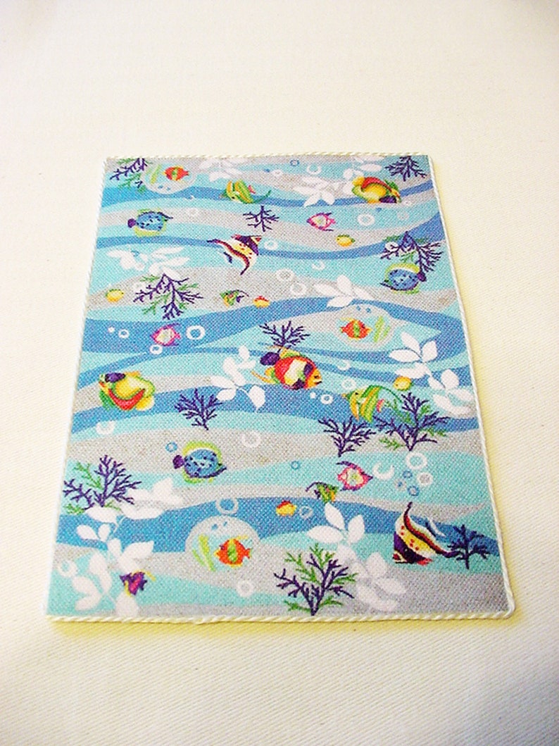 May include: A blue and grey bath mat with a white border. The mat features a repeating pattern of colourful fish, bubbles, and seaweed.