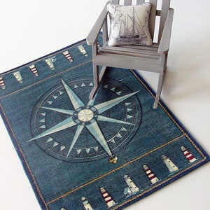 May include: A blue and white nautical rug with a compass design and a border of lighthouses. A rocking chair with a pillow featuring a sailboat is on top of the rug.