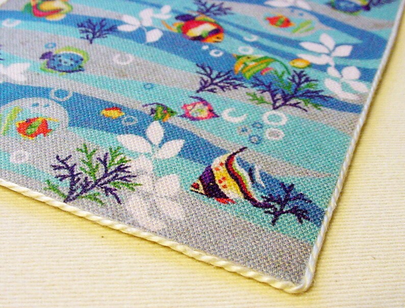 May include: A blue and grey fabric with a white border. The fabric features a repeating pattern of colourful fish, seaweed, and bubbles.