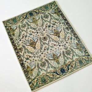 May include: A small, cream-colored rug with a paisley pattern in shades of green, brown, and blue. The rug has a decorative border.